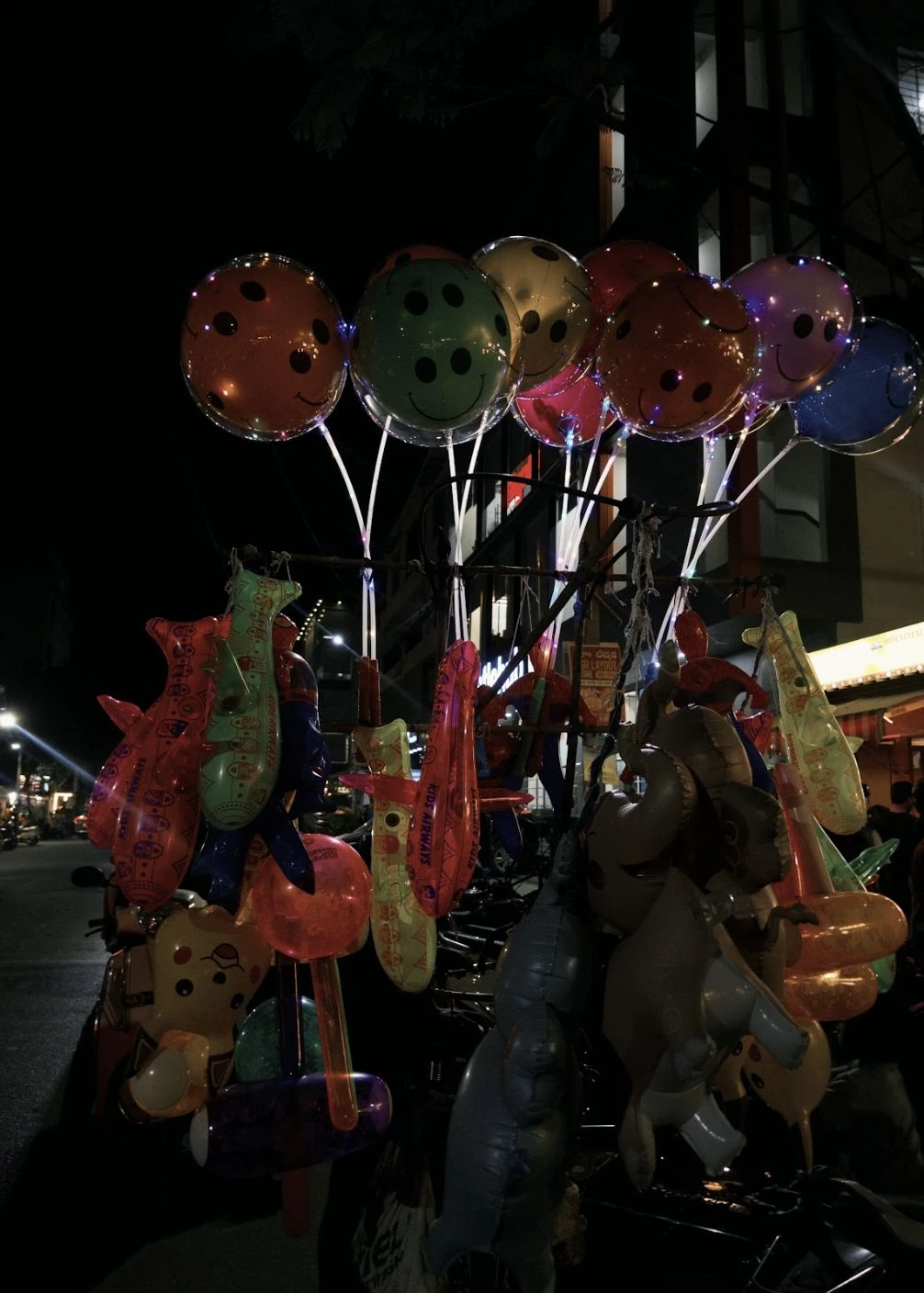 Balloons and colourful toys at a night-time stall.