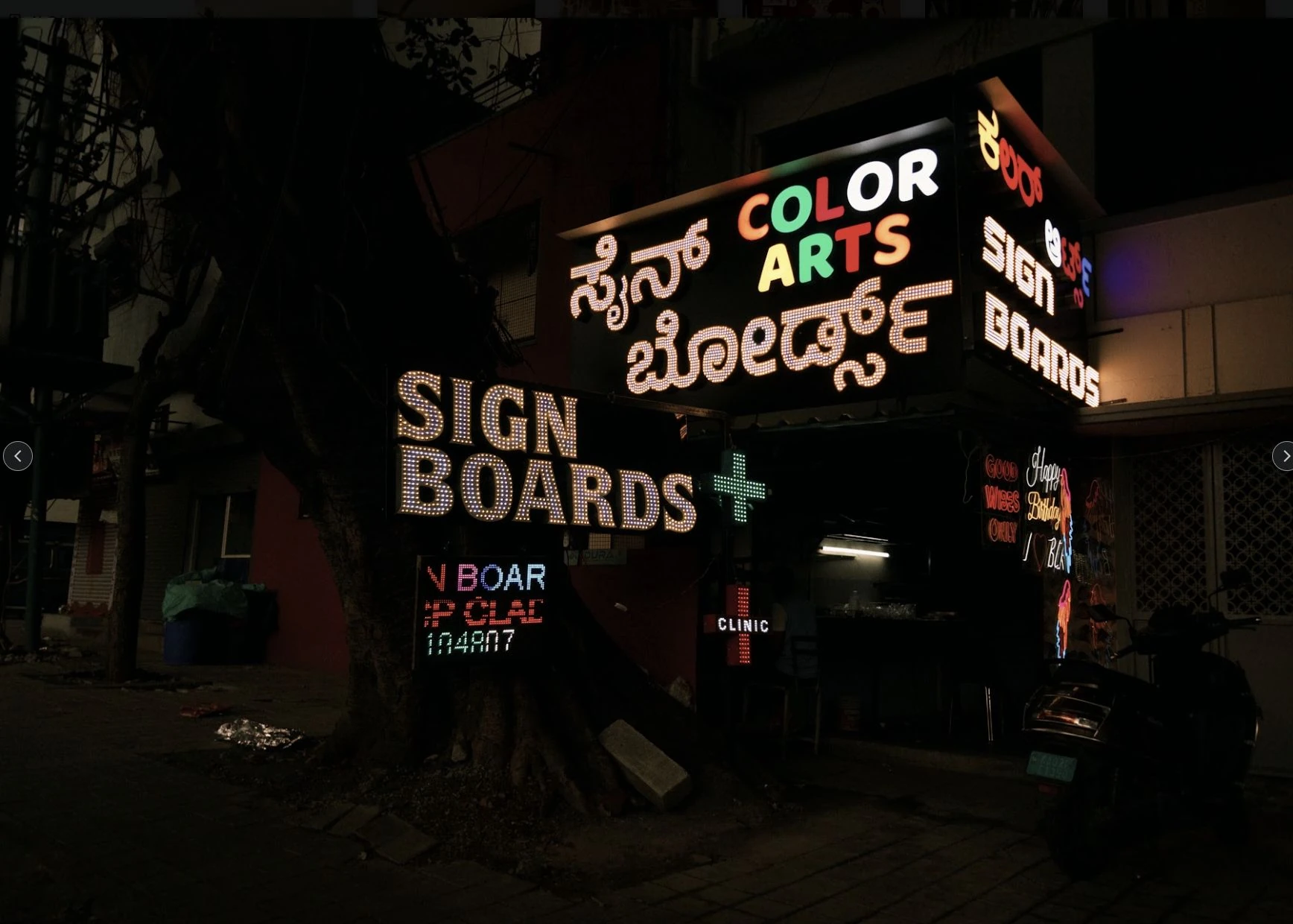 An illuminated sign-painting storefront at night.