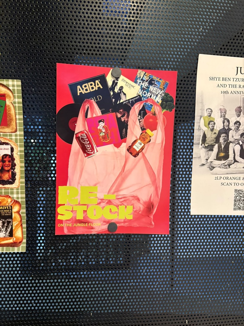 A bright pink record-store poster on a perforated metal wall.